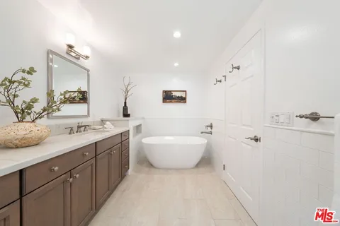 a bathroom with a double vanity sink mirror and bathtub