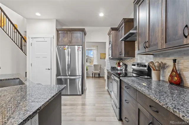 a kitchen with granite countertop stainless steel appliances and refrigerator