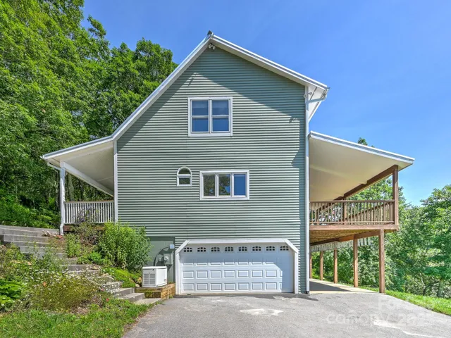 a view of a house with a yard plants and large tree