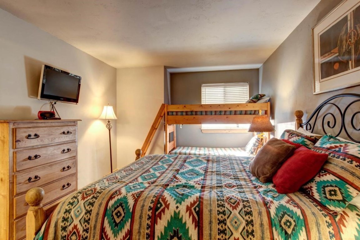 325 Four Oclock Road, Unit A101 Breckenridge, CO 80424 - Photo 14 of 16 a bedroom with a bed and a flat screen tv