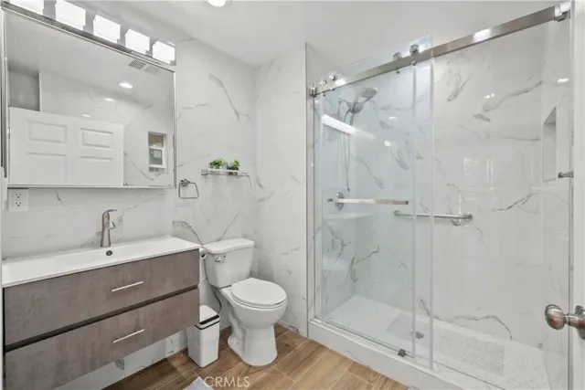 a bathroom with a shower sink vanity mirror and toilet