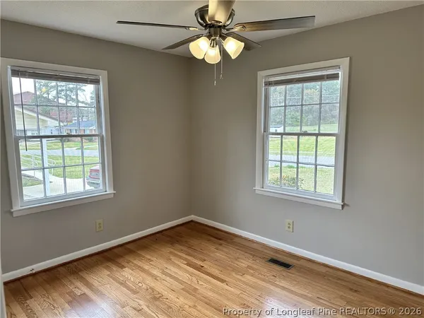 a view of an empty room with wooden floor and a window