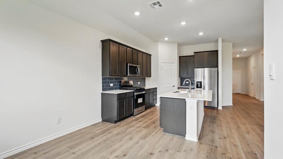 4162 Waldron Trail Forney, TX 75126 - Photo 7 of 29 Kitchen featuring dark wood-finish cabinetry, stainless steel appliances, white countertops, and a dark tile backsplash