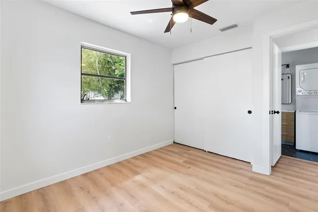 a view of empty room with wooden floor and fan