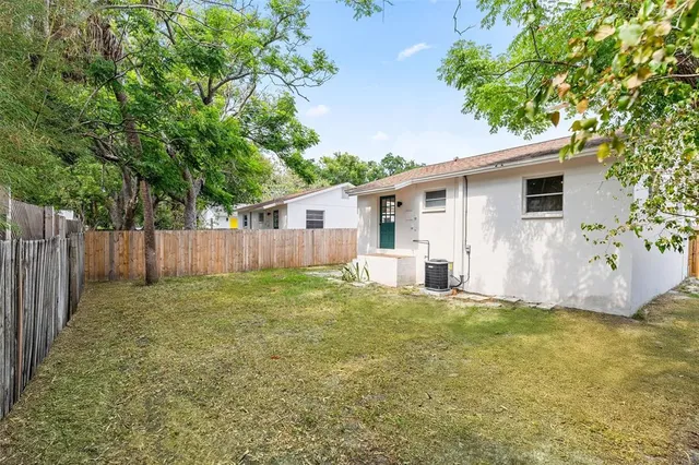 a view of a house with a yard and a large tree