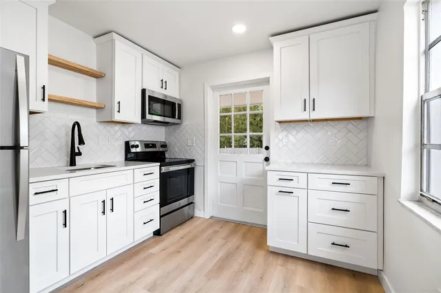 a kitchen with cabinets stainless steel appliances a sink and wooden floor