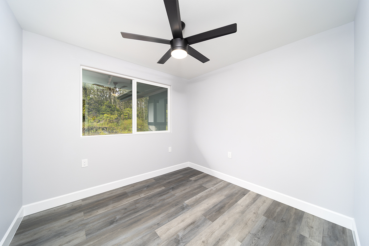 11-3115 Mokuna Street Mountain View, HI 96771 - Photo 23 of 30 an empty room with wooden floor ceiling fan and windows