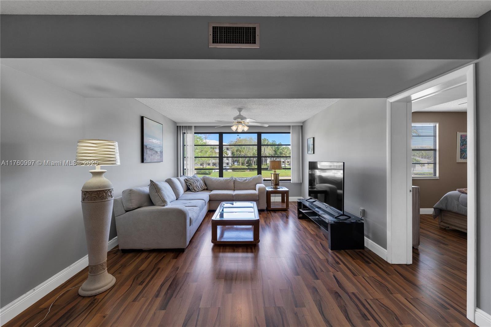 6025 Balboa Circle, Unit 204 Boca Raton, FL 33433 - Photo 17 of 38 a living room with furniture flat screen tv and a large window