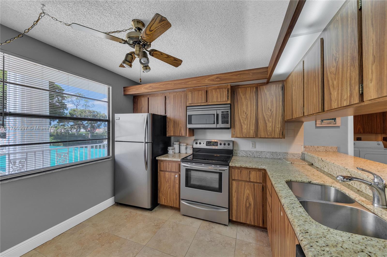 6025 Balboa Circle, Unit 204 Boca Raton, FL 33433 - Photo 6 of 38 a kitchen with stainless steel appliances granite countertop a refrigerator a sink a stove and white cabinets