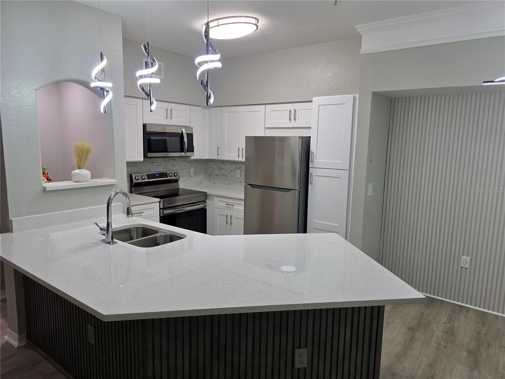 a kitchen with stainless steel appliances a refrigerator sink and microwave