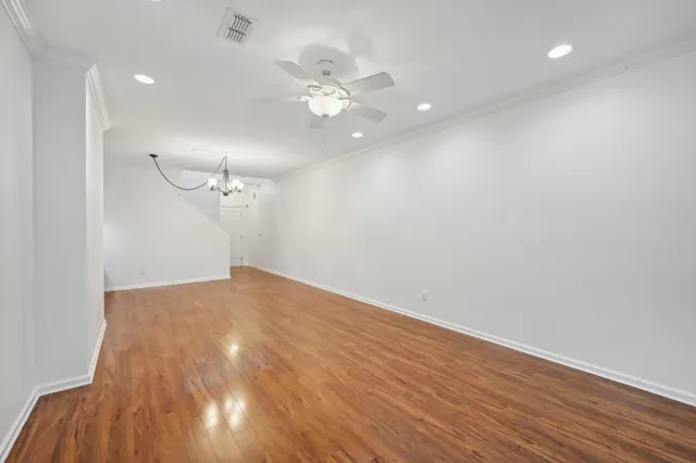 a view of an empty room with wooden floor and a ceiling fan