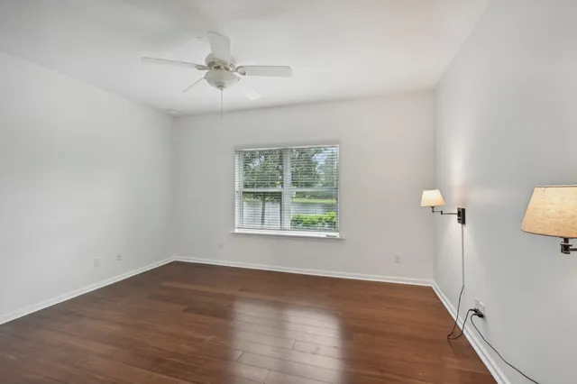 an empty room with wooden floor fan and windows