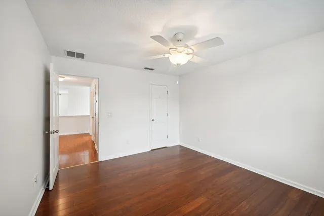an empty room with wooden floor and ceiling fan