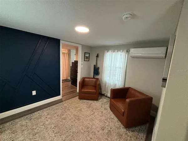 a living room with furniture and a air conditioner vent