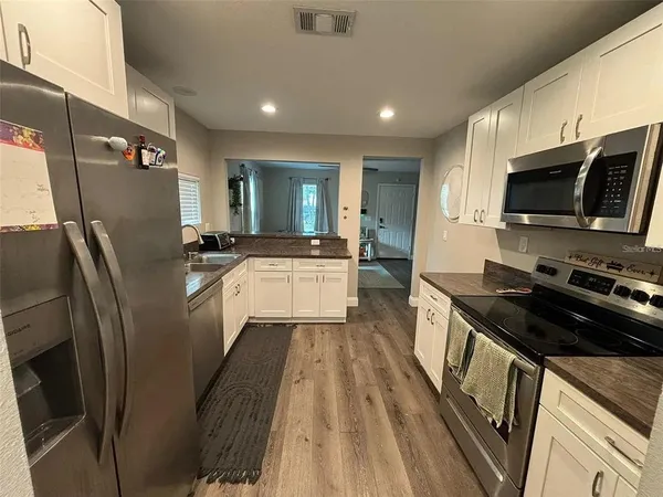 a kitchen with stainless steel appliances a refrigerator a stove a sink a microwave and wooden cabinets