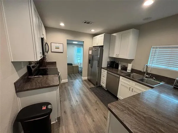 a kitchen with granite countertop a stove top oven a sink dishwasher and a refrigerator with wooden floor