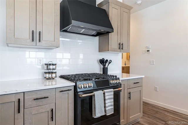 a room with stainless steel appliances a sink dishwasher a stove and a dining table with wooden floor