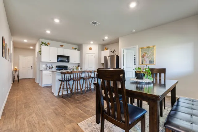 a kitchen with stainless steel appliances kitchen island granite countertop a stove a refrigerator a kitchen island a table and chairs