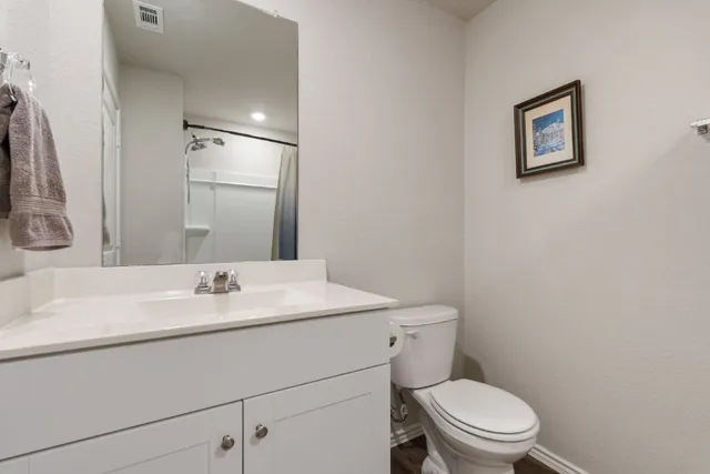 a bathroom with a toilet sink vanity and mirror