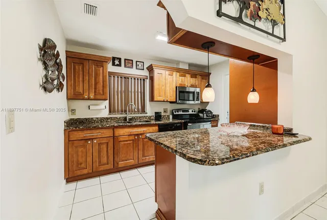 a kitchen with a granite countertop sink and refrigerator