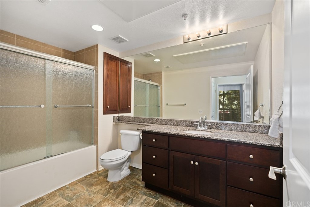 1326 Scholarship Irvine, CA 92612 - Photo 7 of 22 a bathroom with a granite countertop sink toilet a large mirror a bathtub and shower