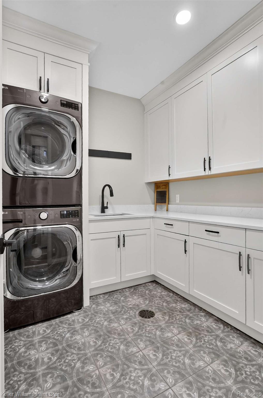1221 North Main Street Rochester, MI 48307 - Photo 27 of 37 Generously sized Laundry Room with decorative ceramic floor, Wood Mode cabinetry, utility sink and oversized stackable LG washer & dryer