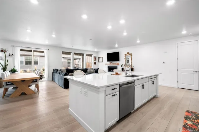 a large white kitchen with lots of counter space a sink appliances and living room view