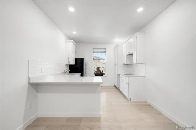a large white kitchen with a refrigerator a stove a microwave and white cabinets