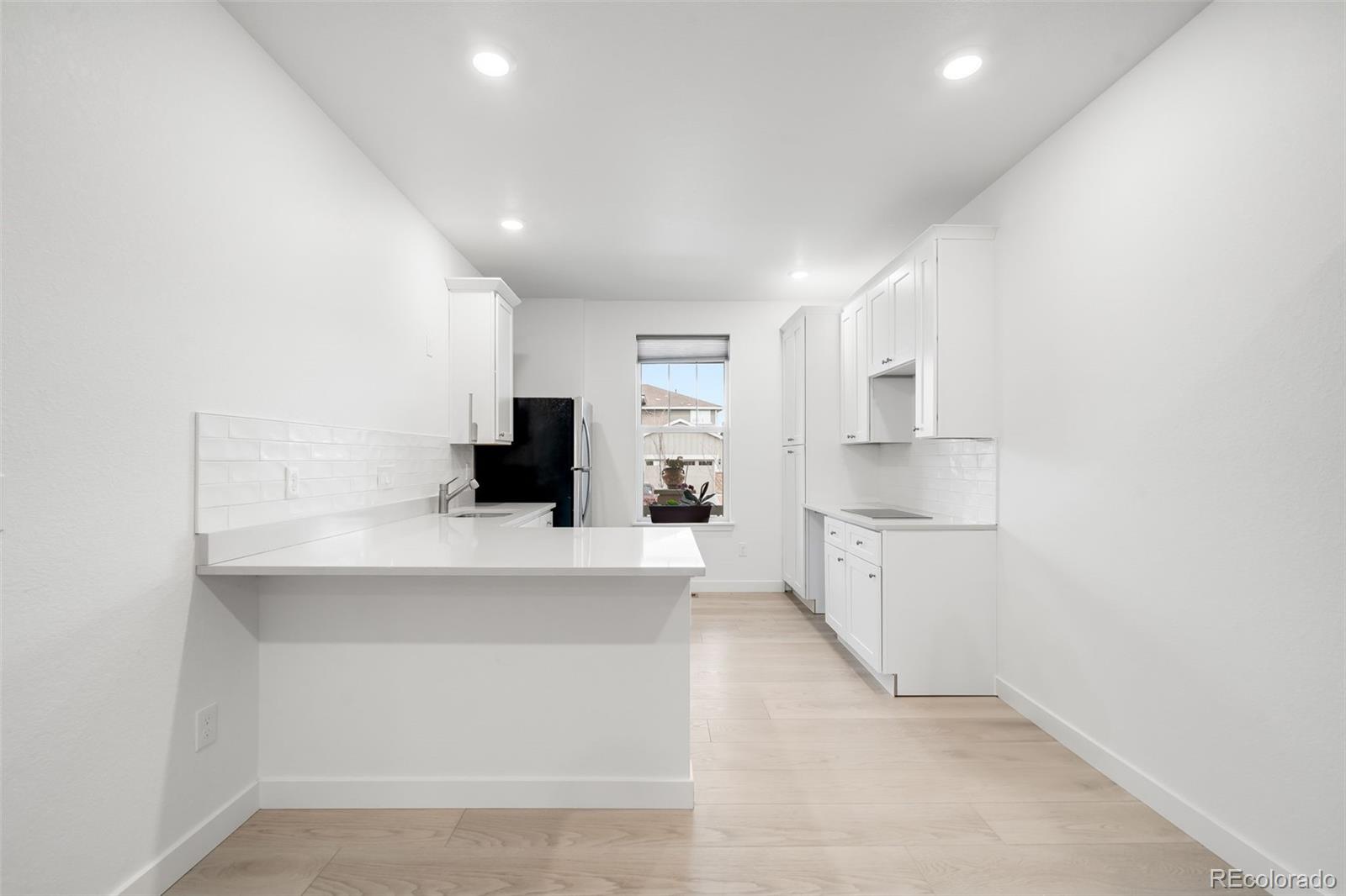 1928 Marlowe Circle West Erie, CO 80516 - Photo 28 of 47 a large white kitchen with a refrigerator a stove a microwave and white cabinets