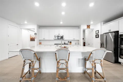 a kitchen with stainless steel appliances a table chairs and a refrigerator
