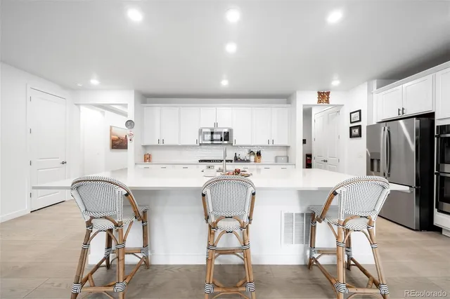 a kitchen with stainless steel appliances a table chairs and a refrigerator