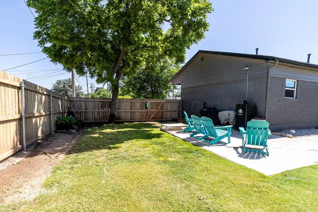 a view of backyard with table and chairs and wooden fence