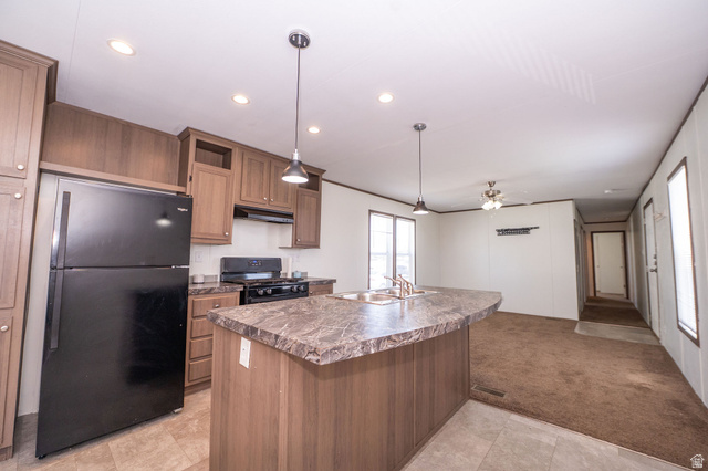 2491 Highway 89, Unit 403 Pleasant View, UT 84404 - Photo 12 of 32 Open concept kitchen featuring wood-finish cabinetry, black appliances, a large island with a double sink, and pendant lighting