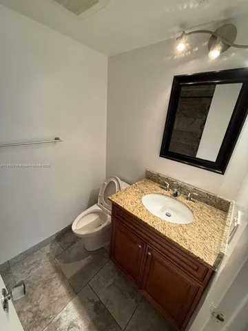 a bathroom with a granite countertop sink a large mirror and toilet