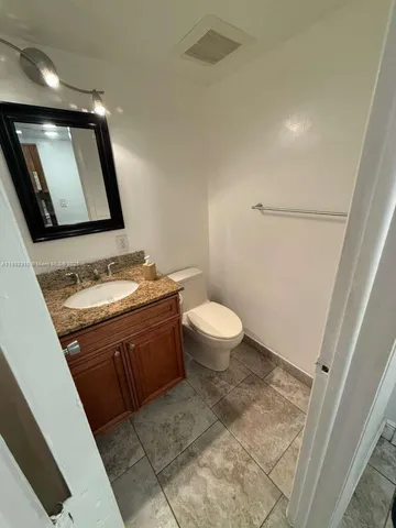 a bathroom with a granite countertop sink a toilet and mirror