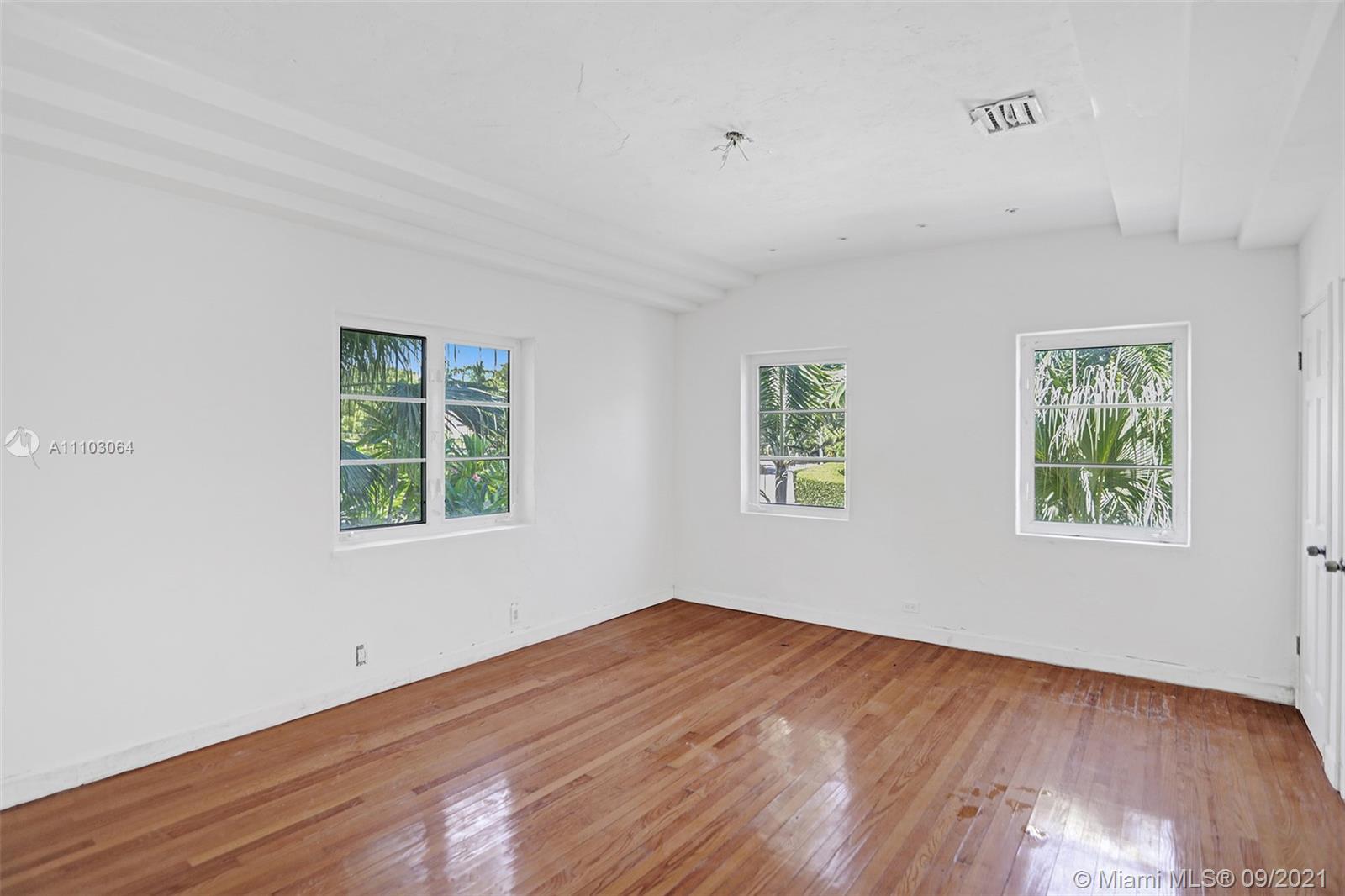 4431 Alton Road Miami Beach, FL 33140 - Photo 35 of 58 an empty room with wooden floor and windows