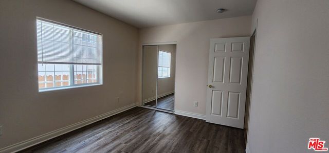 an empty room with wooden floor cabinet and windows