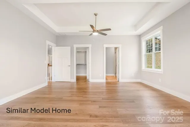 an empty room with wooden floor ceiling fan and windows