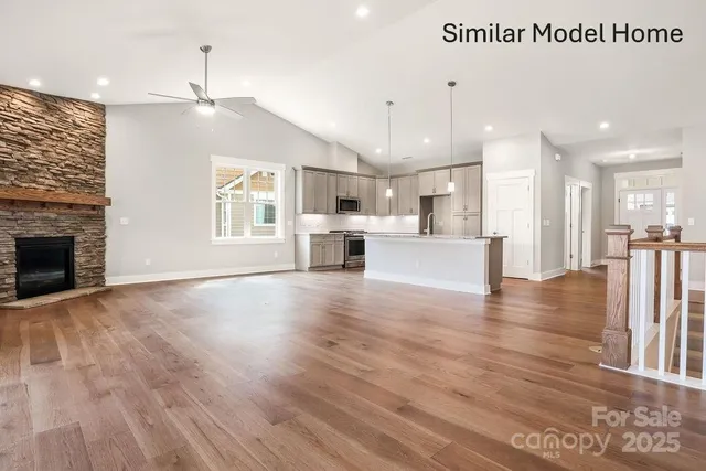 a view of a kitchen and an empty room with wooden floor