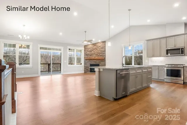 a large kitchen with a large counter top stainless steel appliances and wooden floor