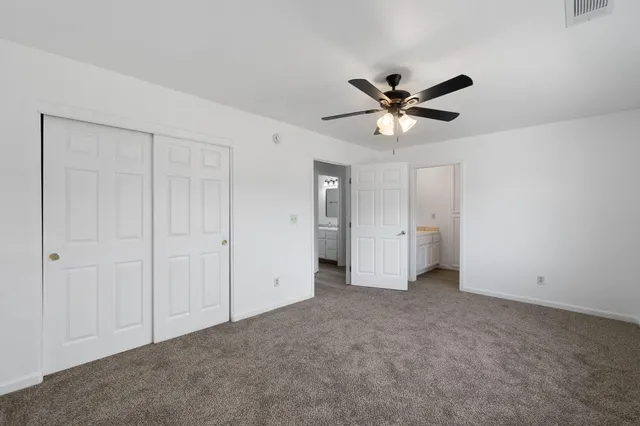 an empty room with closet and a ceiling fan