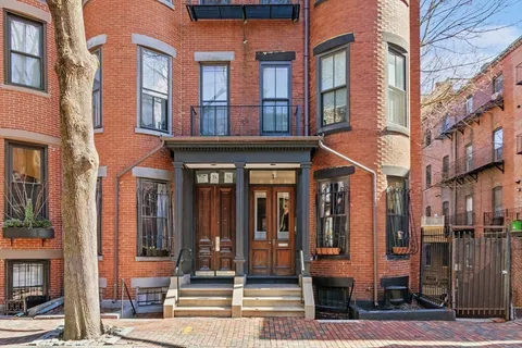 a front view of retail shops with cars parked