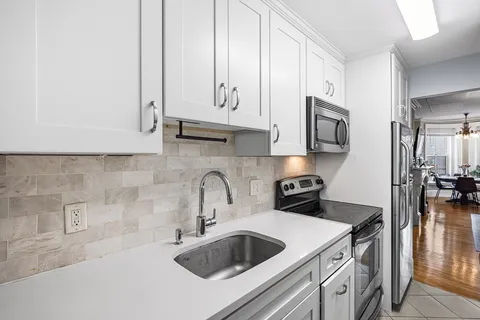 a kitchen with stainless steel appliances granite countertop a sink a stove and white cabinets with wooden floor