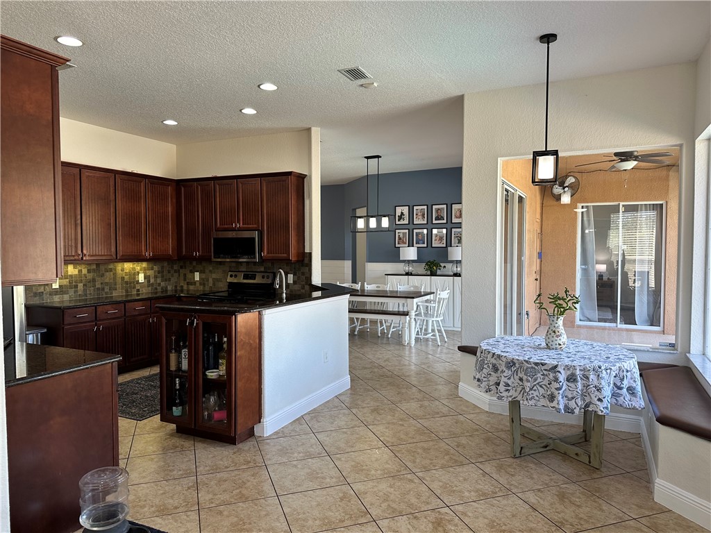 14650 87th Street Fellsmere, FL 32948 - Photo 12 of 36 a kitchen with stainless steel appliances granite countertop a stove top oven a sink a dining table and chairs