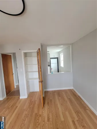 a view of empty room with wooden floor and fan