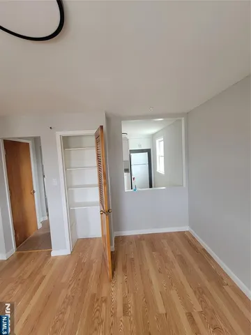 a view of empty room with wooden floor and fan
