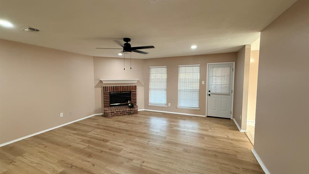 12259 Rim Rock Road Dallas, TX 75253 - Photo 3 of 17 Unfurnished living room featuring a brick fireplace, ceiling fan, light wood-style floors, and recessed lighting