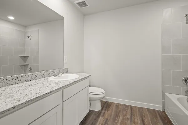 a bathroom with a granite countertop sink a toilet and a mirror