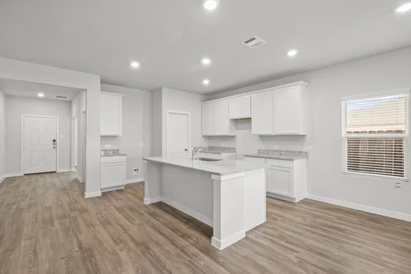 a kitchen with a sink wooden floor and white cabinets