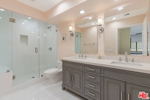 a bathroom with a double vanity sink toilet and shower